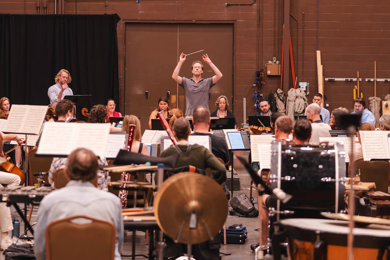 An orchestra conductor directing the orchestra from behind the pit.