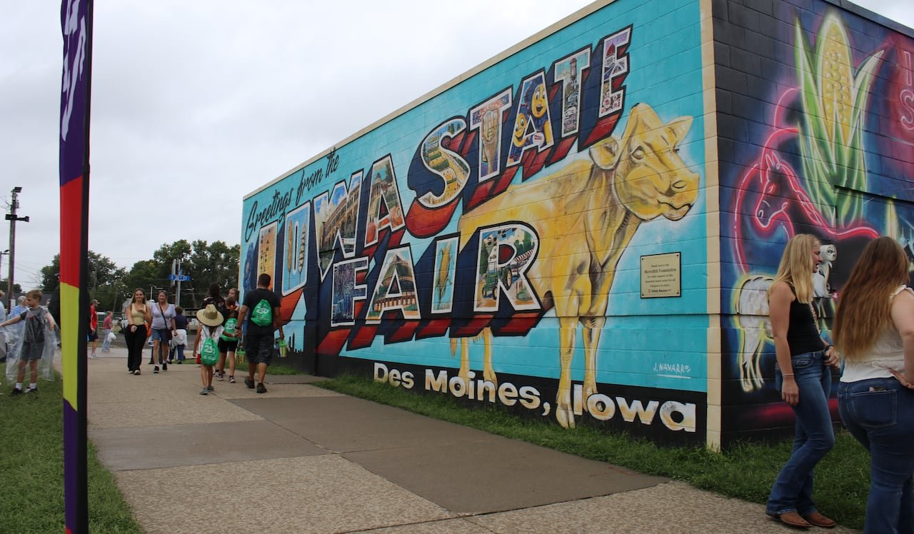 default-304 A colourful mural on the side of a building. The mural features a golden cow and the text "Greetings from the Iowa State Fair."